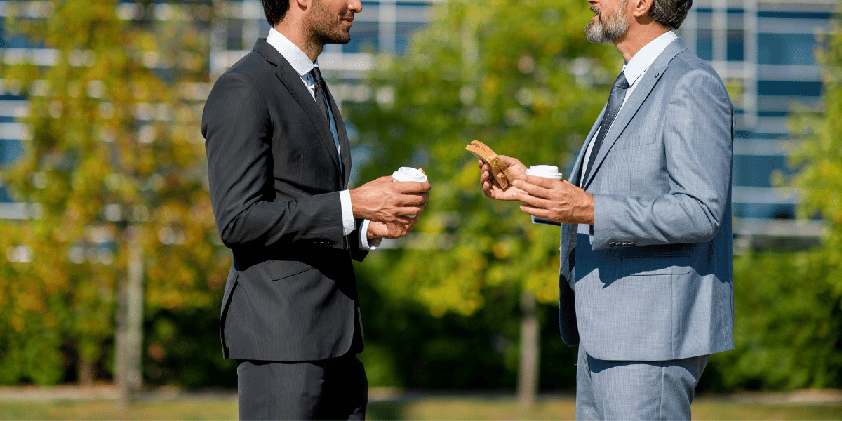 two buisness people eat while discussing work matters