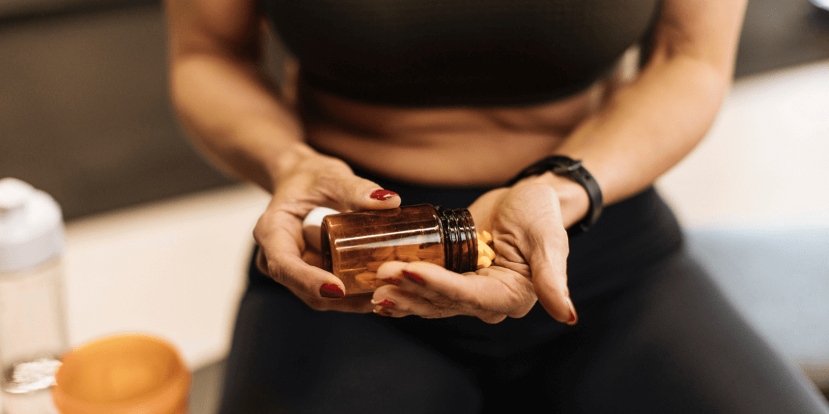 A woman emptying a supplement from a glass bottle into her hand.