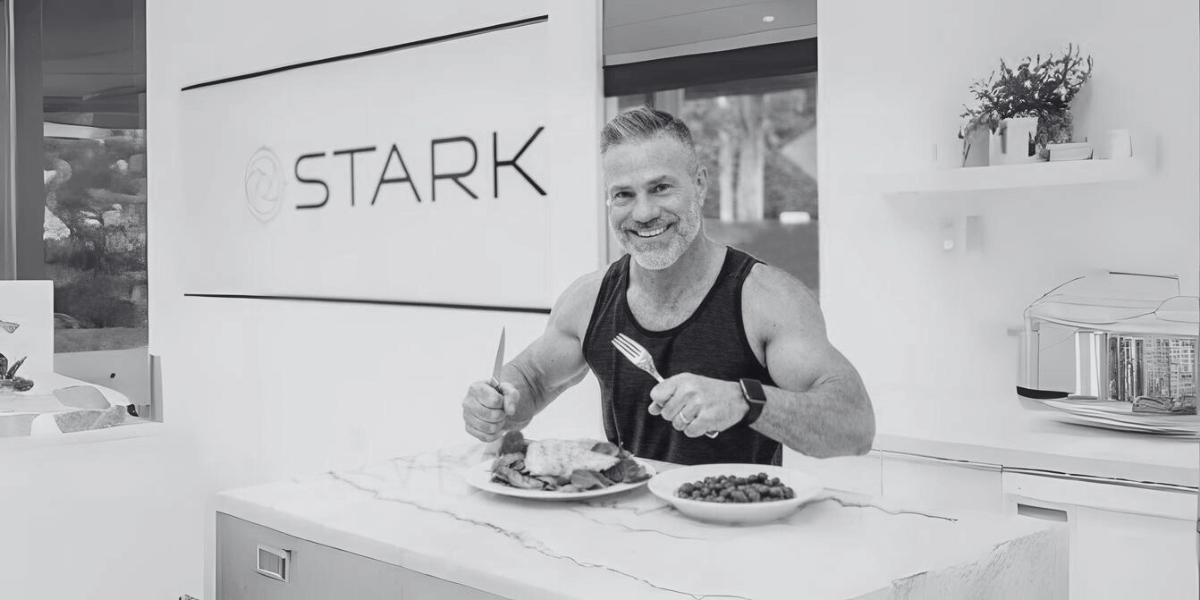 Todd Vande Hei holding a fork and knife with two plates of food in front of him