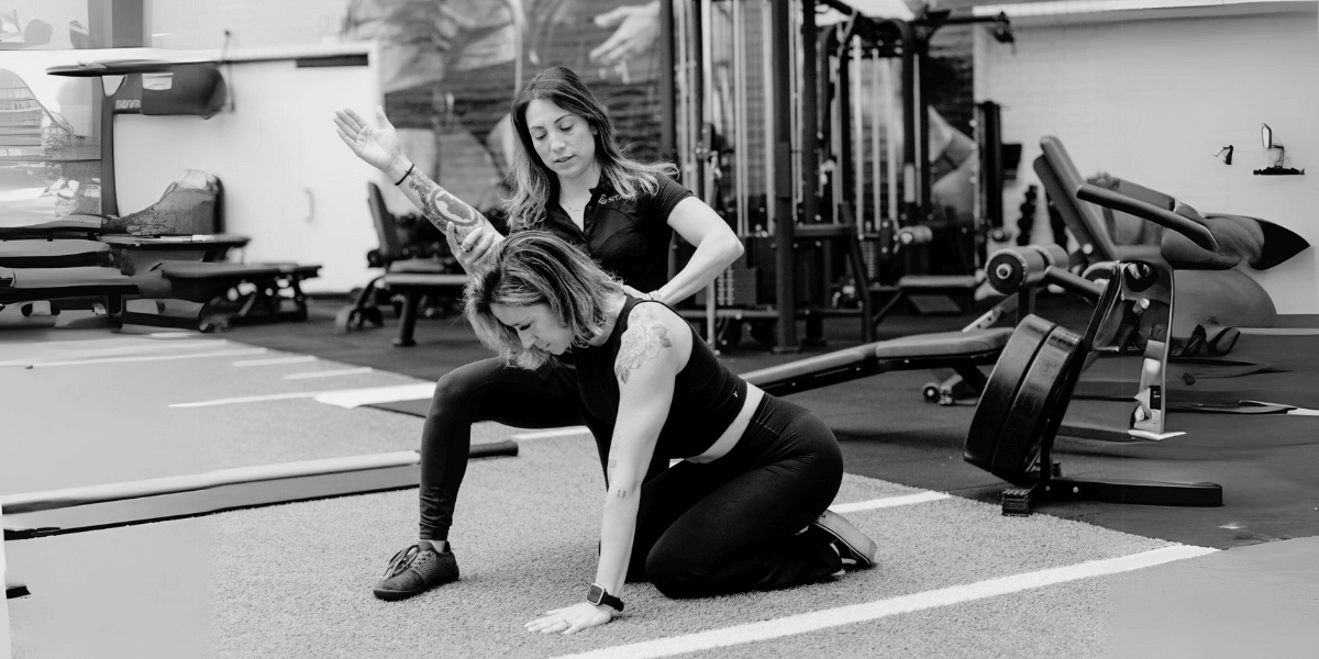 Female Stark trainer coaching a female Stark student in the gym